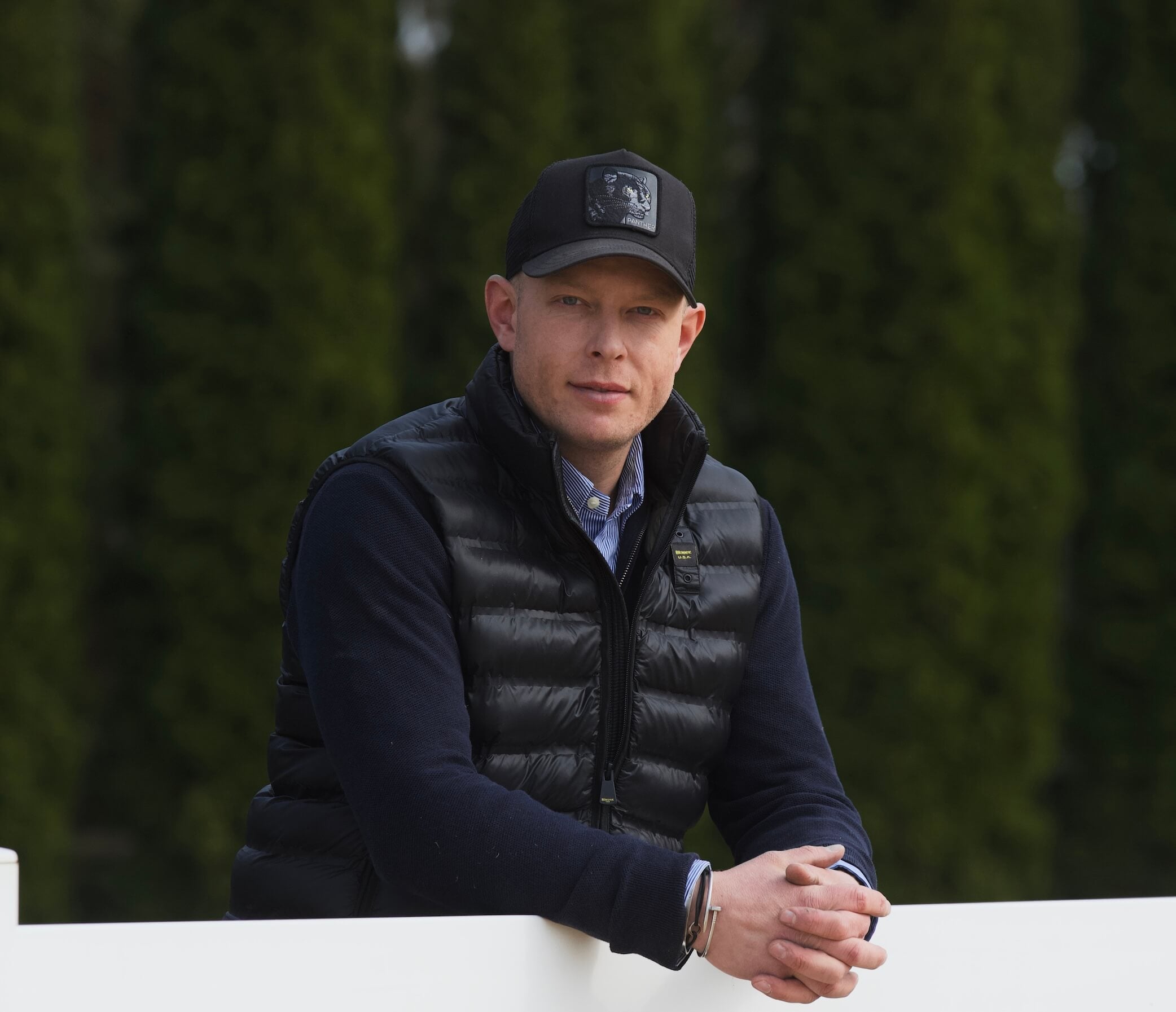 Internationaler Hufschmied Marcus Wagner mit schwarzer Cap und Weste, Bäume im Hintergrund